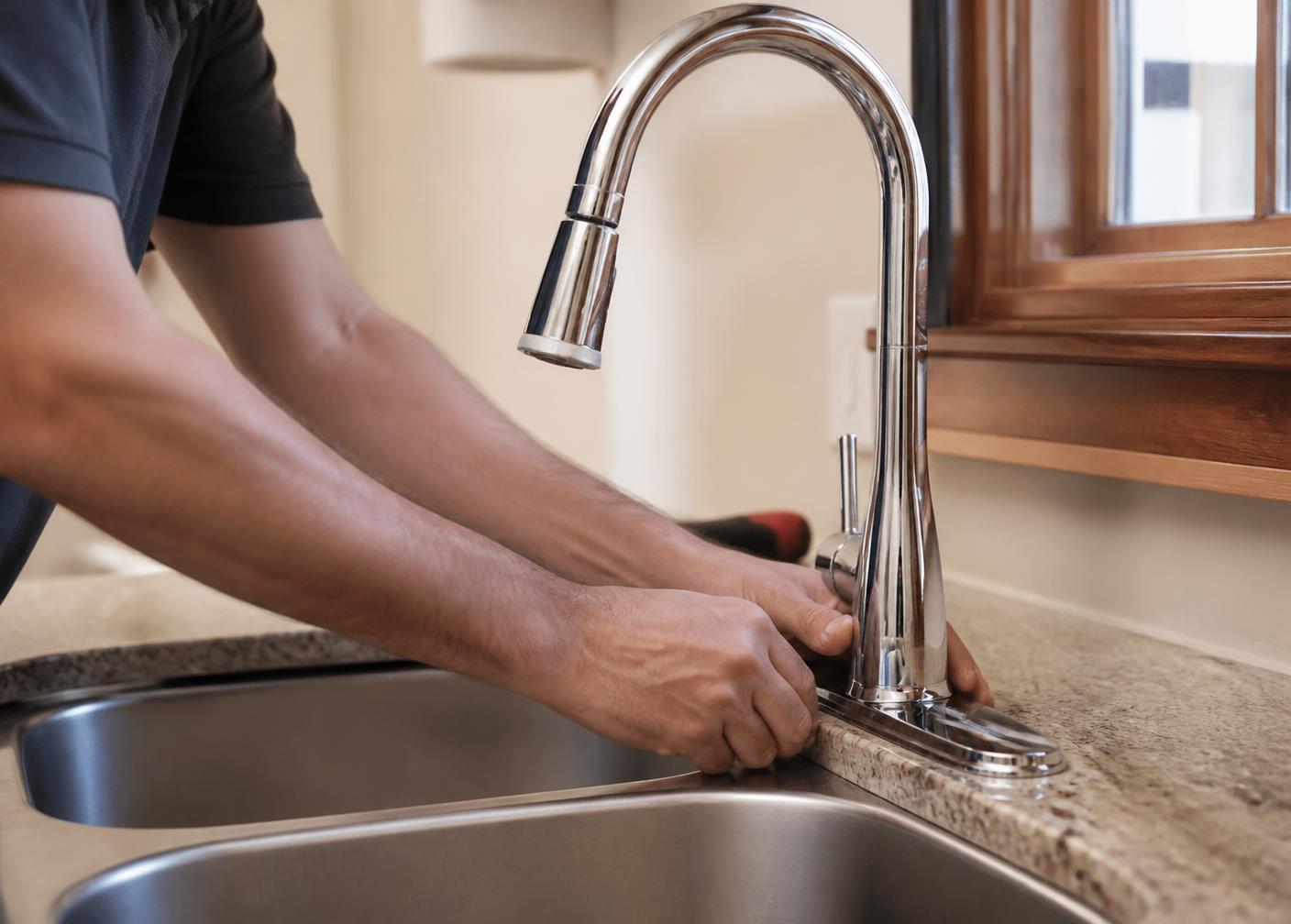 Plumber installing a new kitchen faucet in a home